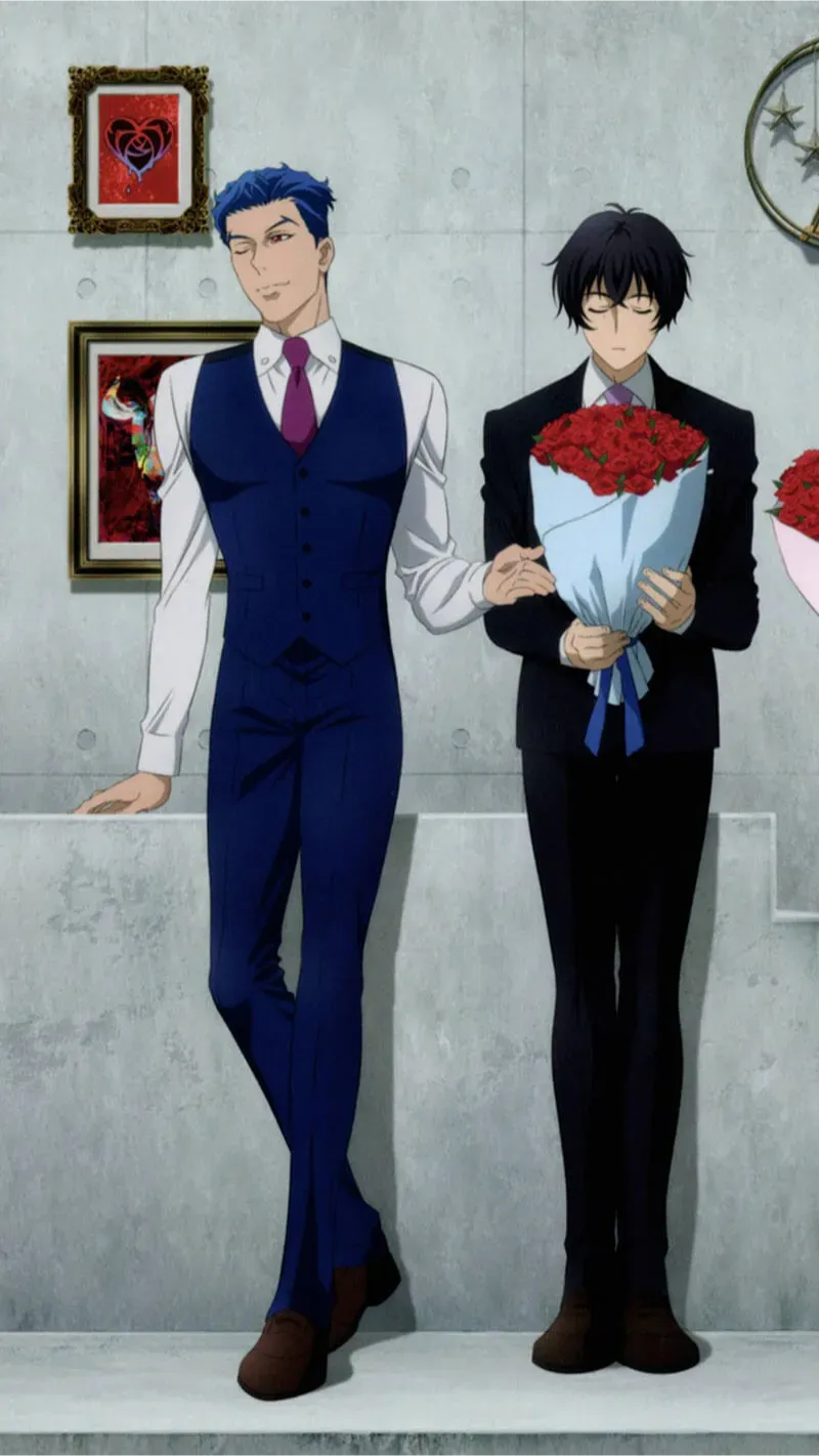 Ainosuke and Tadashi are standing next to each other. Ainosuke is dressed in a blue vest and dress pants. Tadashi is wearing his dark suit while holding a large bouquet of red roses.